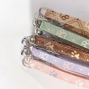 Detailed close-up of colorful pet collars with paw print patterns, metal rings, and bells.