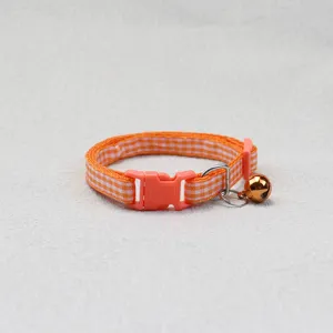 Cute orange plaid pet collar with bell, comfortable fabric dog and cat neck strap detail shot.