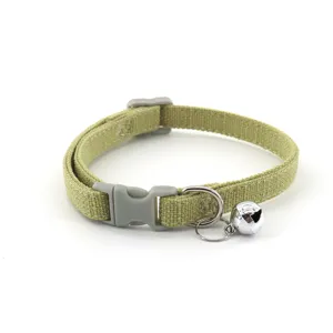 Detail shot of khaki woven pet collar, featuring sturdy plastic buckle and silver bell ornament.