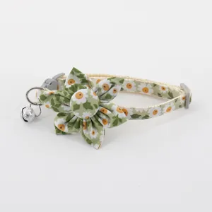 Detail view of the green daisy print pet collar featuring a floral bow and a metal bell.