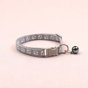 Detailed view of grey pet collar with cute paw prints, quick release buckle and bell.