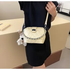 Dettaglio borsa tracolla trapuntata gialla, con catena metallica e simpatico ciondolo.