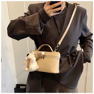 Dettaglio della borsa a mano beige elegante con grazioso ciondolo orsetto e tracolla.