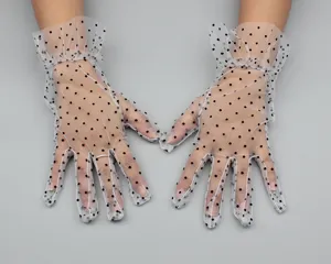 Close-up of white sheer mesh short gloves with black polka dots and delicate ruffles.