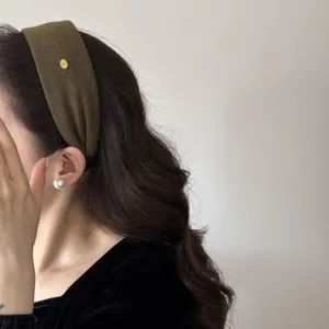 Diadema ancha verde oliva de estilo francés con elegante insignia metálica dorada.
