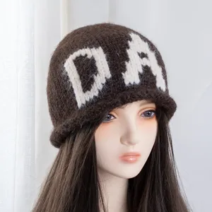 Detalle de gorro de punto marrón para mujer, con patrón blanco DA y dobladillo cálido.