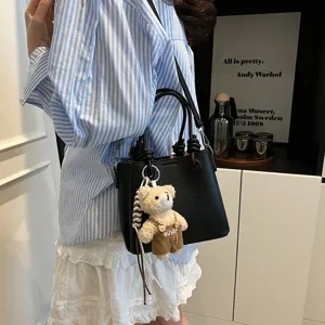 Schicke schwarze Leder-Eimer Tasche mit süßem Bärenanhänger, lässige Umhängetasche für Damen.