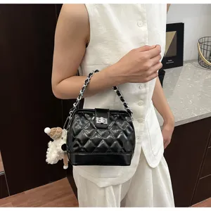 Dettaglio borsa trapuntata nera chic con tracolla a catena, chiusura in metallo e peluche.