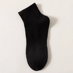 Close-up detail of a classic solid black mid-tube cotton sock with ribbed cuff design.