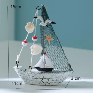 Mediteranes Mini-Segelboot-Ornament mit Netz- und Muscheldetails, ideale Tischdeko.