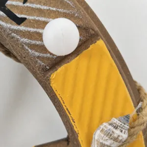 Close-up detail of nautical wooden anchor decor, painted yellow, hemp rope, seashell.
