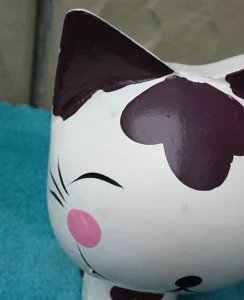 Handcrafted wooden cat figurine detail, showing the cute hand-painted facial expression.
