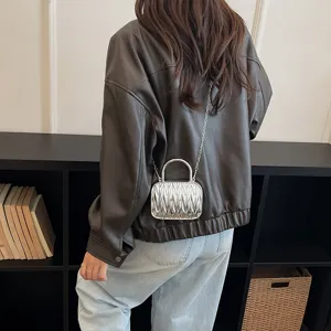 Detail shot of a stylish silver pleated box handbag with chain strap, modern fashion accessory.