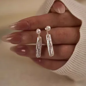 Hermoso primer plano detallado de pendientes colgantes de plata S925 y perlas barrocas.