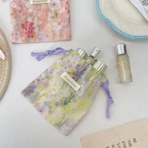 Detailansicht des aquarellgeblümten Stoff-Kordelzugsammelbeutels mit Reiseflaschen.