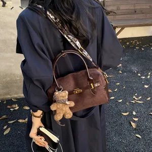 Schicke braune Wildleder Boston Tasche mit breitem Gurt und Bär Anhänger für Damen.