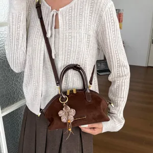 Détail sac à main femme daim marron, sac rétro vintage avec pendentif fleur et poignée.