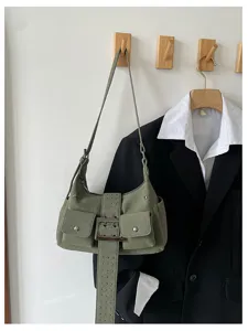 Gedetailleerd overzicht van retro groene suède schoudertas met gesp en voorzakken aan wandhaak.