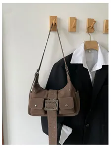 Gedetailleerd overzicht van een bruine vintage suède schoudertas met gesp en voorzakken.