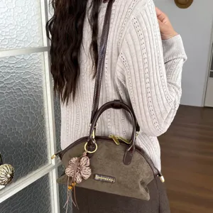 Vue détaillée du sac porté épaule vintage en suédine marron avec pendentif fleur et poignée.