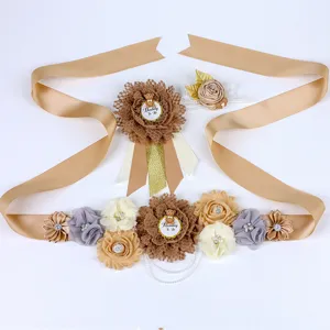 Gedetailleerd overzicht van zwangerschapsband en babyshower badge set met bloemen en beer.