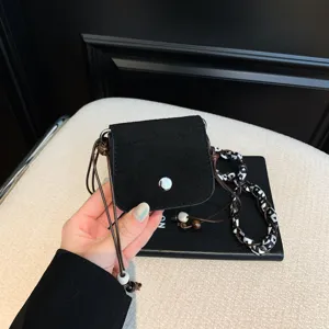 Black suede mini crossbody bag detail, chic women lipgloss pouch with beads and patterned strap.