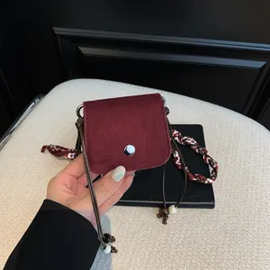 Detail view of the stylish burgundy suede mini pouch with delicate bead charms and snap.