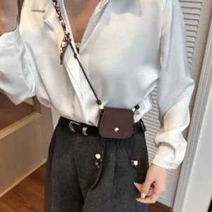 Detailed view of a stylish mini crossbody bag with chic beads and scarf strap for everyday wear.