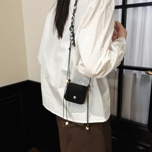 Mini black crossbody bag detail, pendant style with wooden beads, casual daily accessory view.