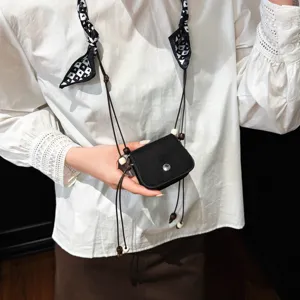 Close-up detail shot of the black mini crossbody bag featuring delicate strings and wooden beads.