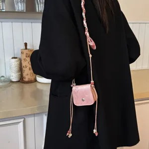 Detail view of a fashionable pink mini crossbody bag with beaded drawstring and chic design.