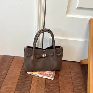 Detailed view of brown suede bucket bag featuring top handles and metal lock detail.