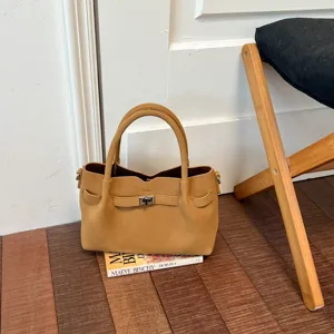 Detailed view of camel suede shoulder bag with metal turn lock closure in cozy setting.