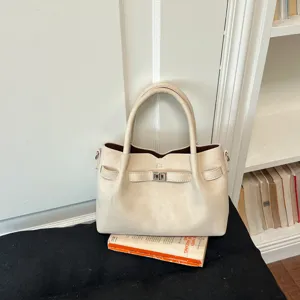 Elegant beige top-handle shoulder bag with turn-lock closure and stylish niche design for women.