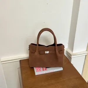 Brown suede handbag with metal turn-lock closure, stylish top-handle shoulder bag for women.