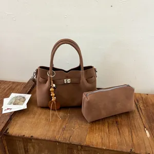 Brown suede handbag set with top handle, metal lock, and matching pouch for women daily use.