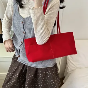 Detailed close-up of the red velvet shoulder bag showcasing its front pocket and soft texture.