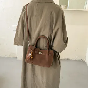 Brown shoulder crossbody bag with top handle and turn lock closure detail for women daily wear.