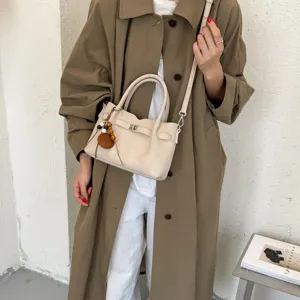 Chic beige shoulder crossbody bag with elegant turn-lock closure and decorative pendant.