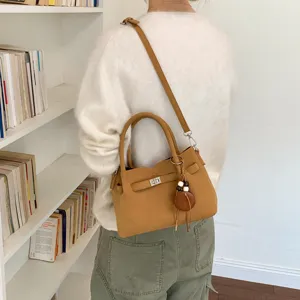 Brown chic shoulder crossbody bag with turn-lock closure and cute hanging charm for women.
