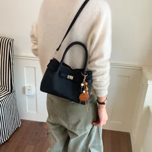 Stylish black shoulder crossbody handbag with turn-lock closure and elegant wooden bead charm for women.