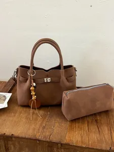 Stylish brown suede handbag and matching pouch set with elegant top handles and charm.