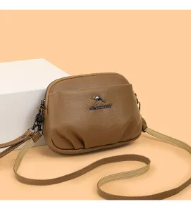 Vue détaillée du sac bandoulière marron en cuir souple, montrant texture et fermoirs.