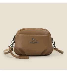 Sac bandoulière souple en cuir marron pour femme avec logo kangourou en métal style minimaliste.