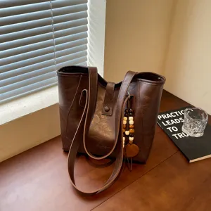 Vista detallada del bolso tote vintage marrón oscuro con decoración de abalorios de madera.