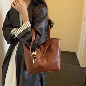Vista detallada del bolso tote vintage de cuero PU marrón con elegante colgante de abalorios.