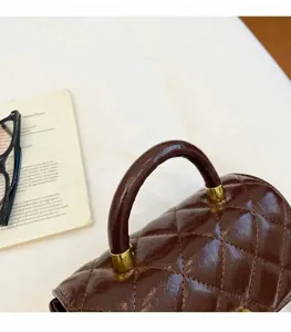 Dettaglio borsa a mano trapuntata marrone, elegante borsetta quadrata per autunno.