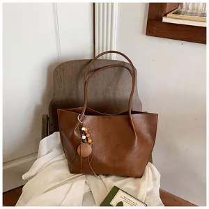 Detalle del bolso tote vintage marron con gran capacidad y colgante de cuentas de madera.