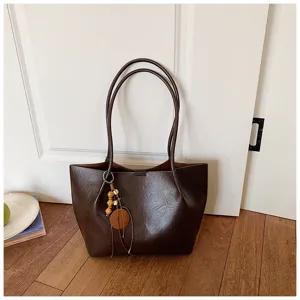 Vista detallada de bolso tote vintage marrón oscuro con colgante de madera minimalista.