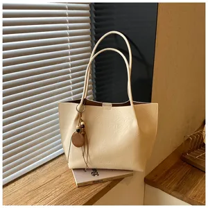 Vista detallada del bolso tote beige informal con correas y abalorios de madera en la mesa.